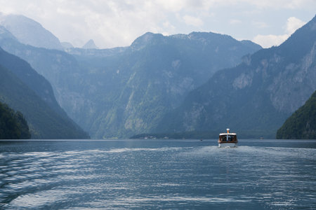Sailing on beautiful alpine lake surrounded by steep mountain walls, Konigssee, Germanyの写真素材