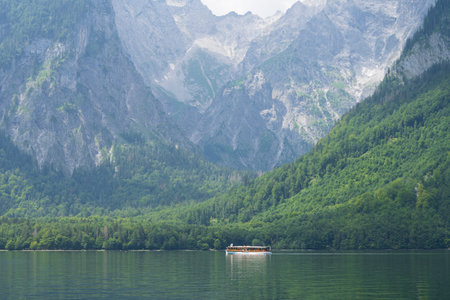 Small boat sailing on alpine lake surrounded by high mountains , Konigssee, Germanyの写真素材