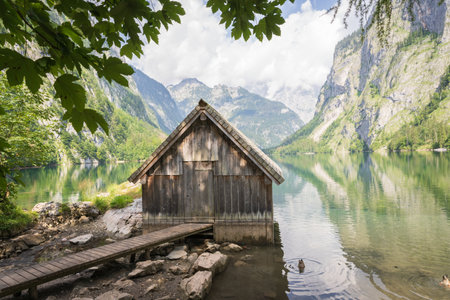 Old wooden boathouse with boardwalk on a pristine alpine lake surrounded by mountains, Germanyの写真素材