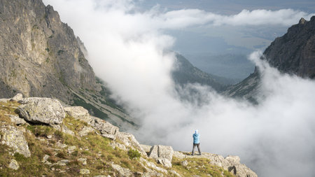 Man enjoying the view on beautiful alpine valley shrouded with low clouds, Slovakia, Europeの写真素材