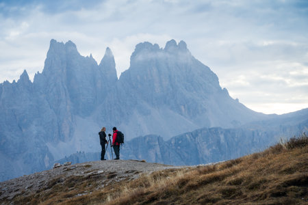 Two landscape photographers talking in front of impressive rock wall of mountains, Italy, Europeの写真素材