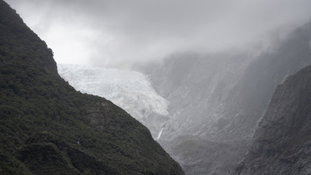 Massive glacier flowing into a valley through steep rock walls shot in New Zealandの写真素材