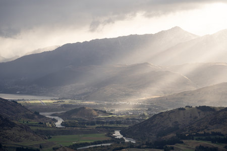 Beautiful landscape shot of town in a valley surrounded by mountains during warm sunset, New Zealand