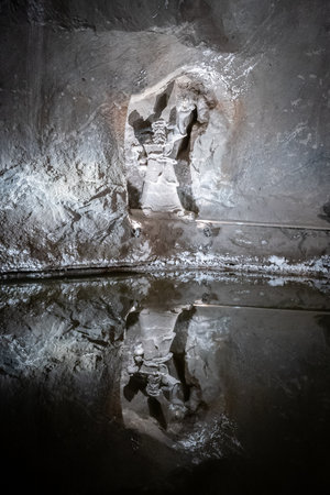 Stone statue carved into stone wall located in underground mine with water reflections, Krakowの写真素材