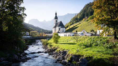 Picturesque church in alpine village surrounded by mountains and autumn trees, Hintersee, Germany