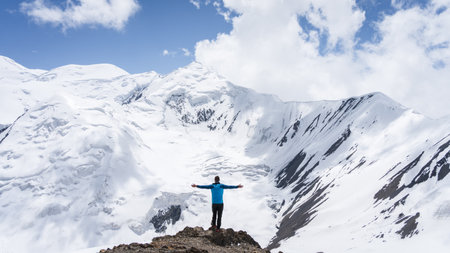 Solitary man standing on the top of the mountain with huge mountains around him, Pamir, Kyrgyzstanの写真素材