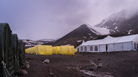 View on expedition camp with many tents under snowy peaks during sunset, Pamir Mountains, Kyrgyzstanの写真素材
