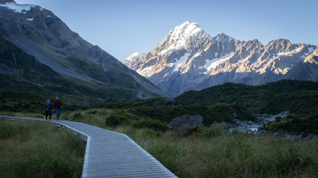 Happy couple walking on a trail with snowy mountain in backdrop, Mt Cook, New Zealand