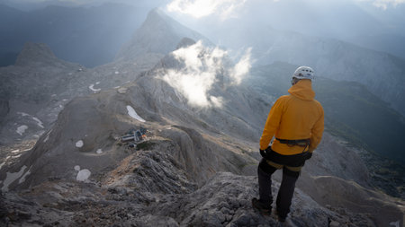 Hiker standing on top of a mountain looking down on beautiful alpine landscape below, Slovenia