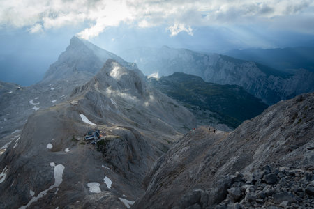 Alpine landscape with hikers and mountain hut lit by early morning soft light, Sloveniaの写真素材