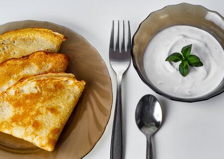 tasty pancakes with sour cream on a plateの写真素材