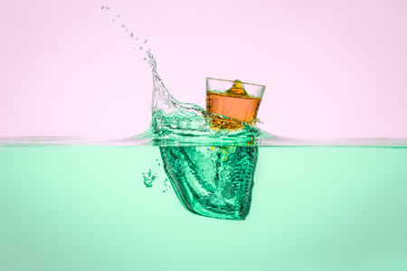 Orange vodka falling into the water making water splashの写真素材
