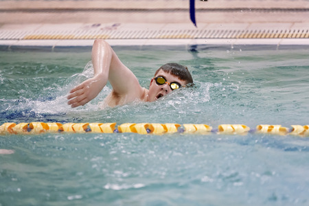 Young swimmer practicing freestyle in swimming pool before competition.