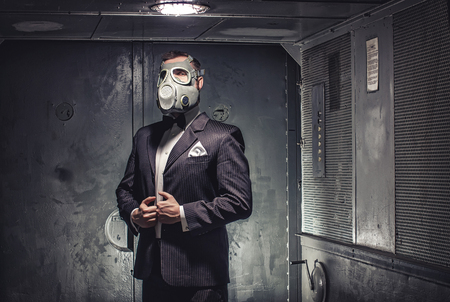 Man in gas mask and suit, standing in old elevator. Secret agent, terrorist or businessman of apocalypse?の写真素材