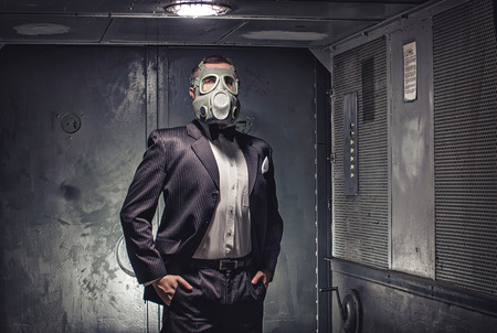Man in gas mask and suit, standing in old elevator. Secret agent, terrorist or businessman of apocalypse?の写真素材