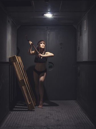 Young, athletic and beautiful woman standing in old, retro elevator with pallets. Dark color toned picture.の写真素材