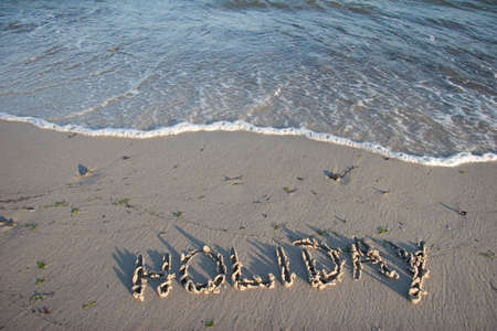 HOLIDAY painted in the sand on the beachの写真素材