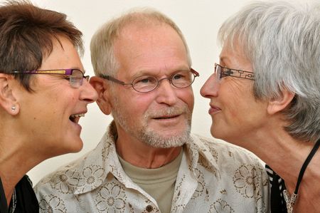 Senior listening to his two girl friendsの写真素材