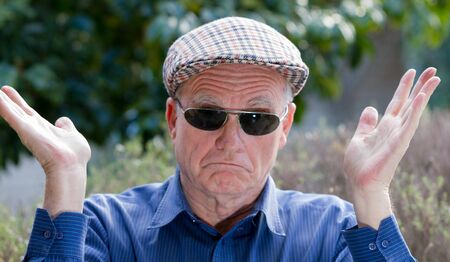 Elderly man in sunglasses looking very dissatisfied with the worldの写真素材