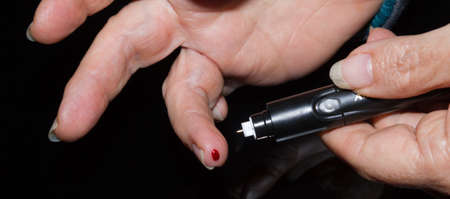 Woman with diabetes type 2 takes blood drop to test blood sugar levelのeditorial素材