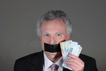 Crooked politician or businessman with bribe with money to buy his silenceの写真素材