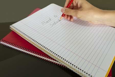 teacher writing back to school in notebook
