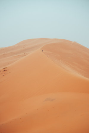 People climbing Erg Chebbi dunes in Sahara Desert, Merzouga, Moroccoの写真素材