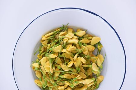 Yellow flower Sesbania isolated on tile dish with a white background.の写真素材