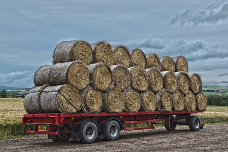 Artistic image of a trailer loaded with straw bales ready for transportの写真素材