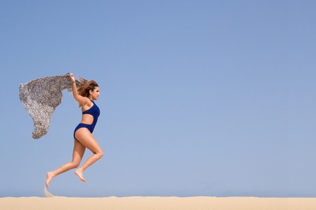 Pretty brunette running in the sandの写真素材