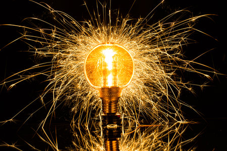 Isolated sparkling exploding electric light bulb on black backgroundの写真素材