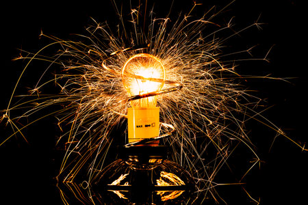 Isolated sparkling exploding electric light bulb on black backgroundの写真素材