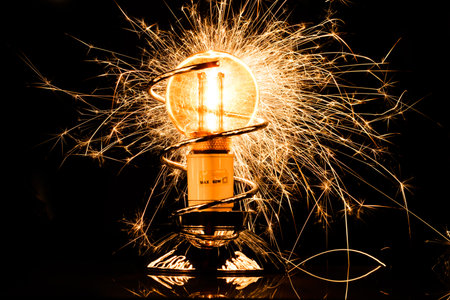 Isolated sparkling exploding electric light bulb on black backgroundの写真素材