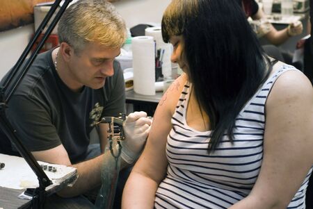 SAINT PETERSBURG - JUNE 20, 2010: Tattoo artist at work at St.Petersburg Tattoo Festival  - a four-day event on  art of tattooing, body modification, body art  in St. Petersburg, Russia.のeditorial素材