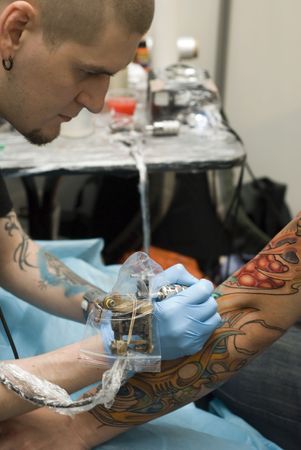 SAINT PETERSBURG - JUNE 20, 2010: Tattoo artist at work at St.Petersburg Tattoo Festival - a four-day event on art of tattooing, body modification, body art June 20, 2010 in St. Petersburg, Russia. のeditorial素材