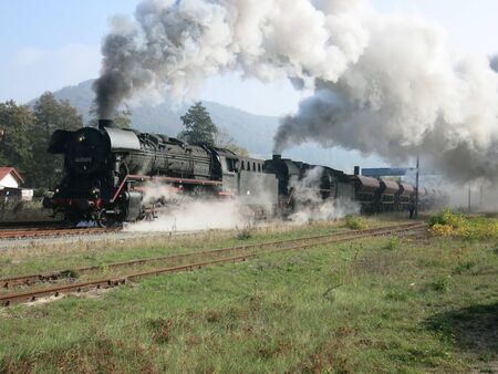 Two steam locomotives in front of freight train leave