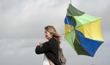 Woman struggles onto her inside out umbrellaの写真素材