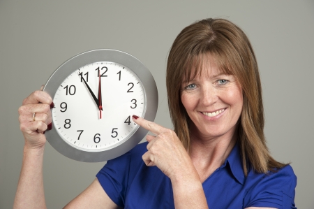 Woman with surprised expression holding a clockの写真素材