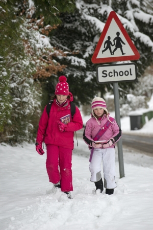 Children walking to school along a snow covered roadの写真素材