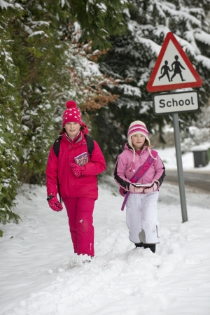 Children walking to school along a snow covered roadの写真素材