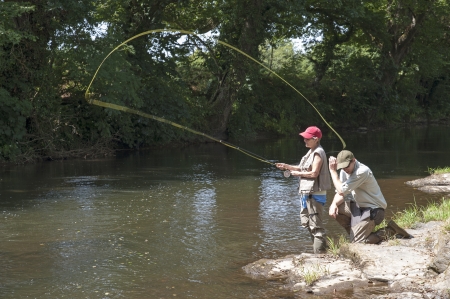 Fly fishing a gillie instructing a pupil River Lyd Devon UKの写真素材