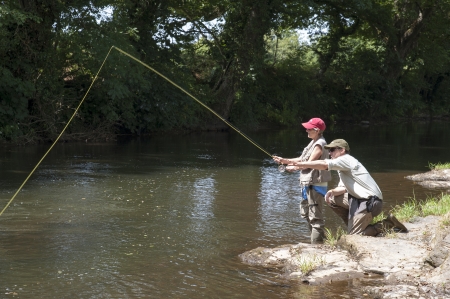 Fly fishing a gillie instructing a pupil River Lyd Devon UKの写真素材