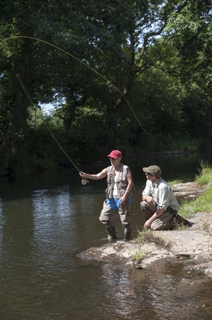 Fly fishing a gillie instructing a pupil River Lyd Devon UKの写真素材