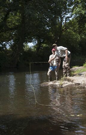 Fly fishing a gillie instructing a pupil River Lyd Devon UKの写真素材