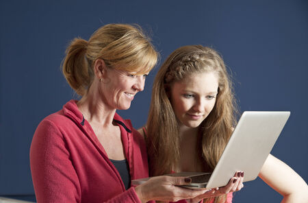 Adult and teenager looking at a laptop computerの写真素材
