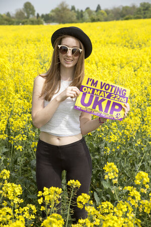 First time voter teenage girl in felt hat holding UKIP poster