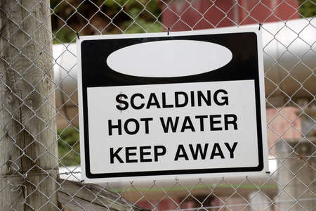 Danger notice on wire fence Scalding Waterの写真素材
