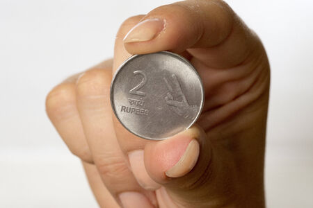 Indian two Rupee coin held between fingersの写真素材