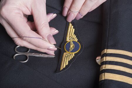Sewing wings onto a uniform jacketの写真素材