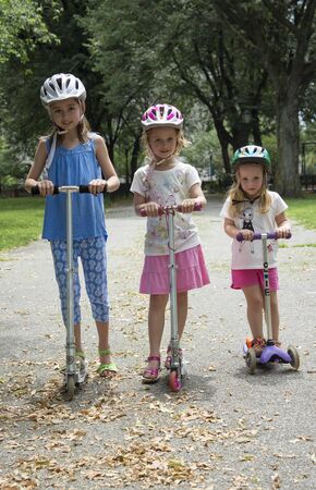 Three children riding scooters in a New York park, USAのeditorial素材